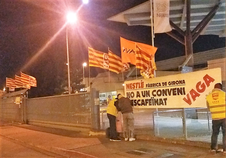 Treballadors de Nestlé fixen una pancarta a la porta de la fàbrica, foto: UGT Girona