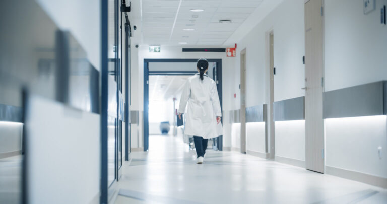 ActualitatDesgavell protocolari a les portes de noves aturades mèdiques Female Doctor Walking Away in an Empty Hospital Hallway. General Practitioner Holding a Tablet Computer while Going to Intensive Care Unit or General Medicine Ward for Daily Patient Visit